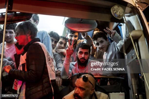 People gesture from a Red Cross bus carrying Palestinian prisoners released from Israeli jails in exchange for hostages released by Hamas from the...