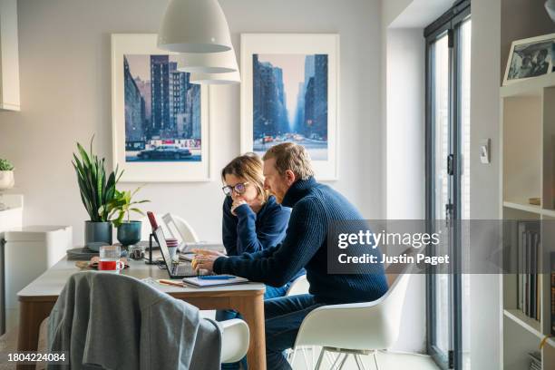 side view of a mature man and mature woman working from home - they are collaborating on a project - shopping online blue stock pictures, royalty-free photos & images