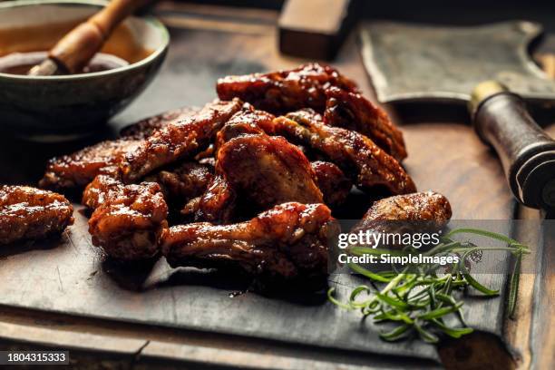 baked chicken wings with sesame seeds and sweet chili sauce on wooden cutting board. barbecue chicken wings close up on wooden tray. - poultry netting stock pictures, royalty-free photos & images