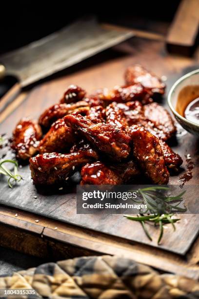 baked chicken wings with sesame seeds and sweet chili sauce on wooden cutting board. barbecue chicken wings close up on wooden tray. - poultry netting stock pictures, royalty-free photos & images