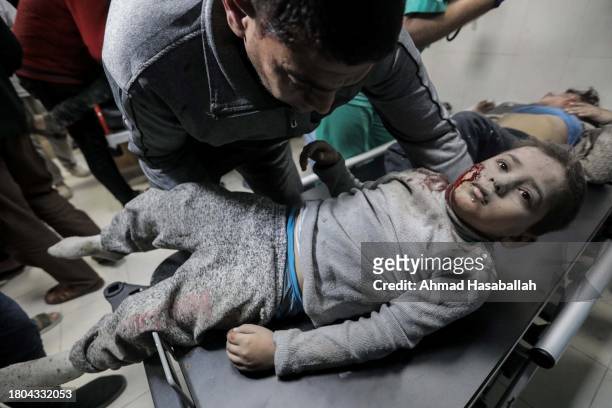 Man places an injured boy on a stretcher as Palestinians injured in airstrikes arrive at Nasser Medical Hospital on November 20, 2023 in Khan Yunis,...