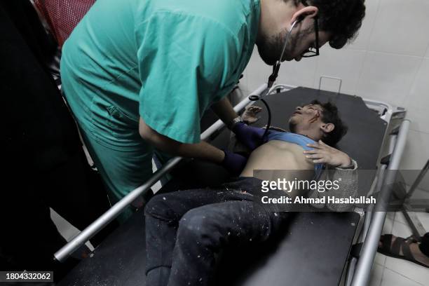 Man tends to a young boy on a stretcher as Palestinians injured in airstrikes arrive at Nasser Medical Hospital on November 20, 2023 in Khan Yunis,...