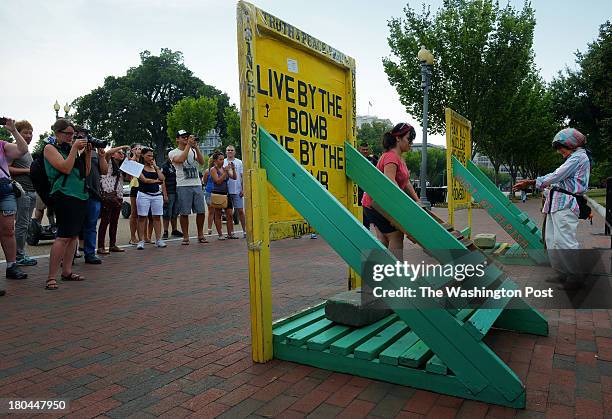 Spectators watch as Connie Picciotto, right, and fellow activist Feriha Kaya, center, reassemble her peace vigil tent, which was taken down last...