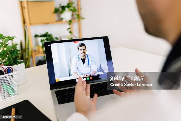 mid adult man talking with male doctor through laptop video call - social distancing hospital stock pictures, royalty-free photos & images