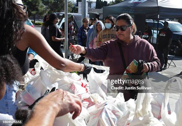 Volunteers pass out free bags of food during the 3rd annual Los Angeles Police Department's turkey drive at Wilshire Station on November 20, 2023 in...