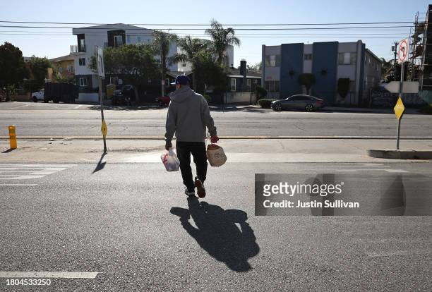 Man carries away a bag of food and a free turkey during the 3rd annual Los Angeles Police Department turkey drive at Wilshire Station on November 20,...