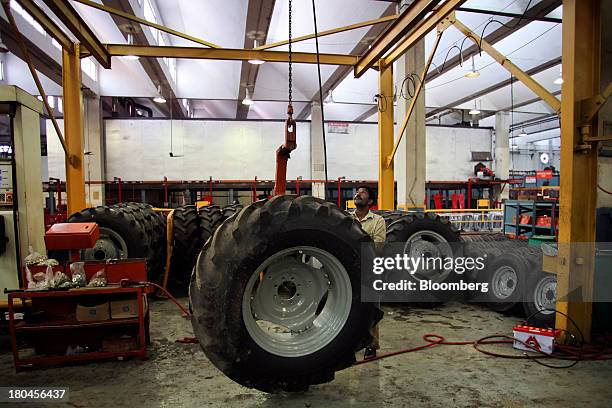 An employee arranges tractor tires on the production line of the Millat Tractors Ltd. Assembly plant in Lahore, Pakistan, on Thursday, Aug. 29, 2013....