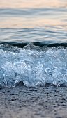 Macro shot of calm blue sea waves rolling and breaking on a sea beach on sunset