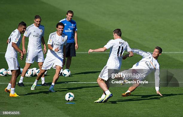 Real Madrid's new signing Gareth Bale is tackled by Cristiano Ronaldo while teammates Jese Rodriguez , Karim Benzema , Pepe and assistant coach...