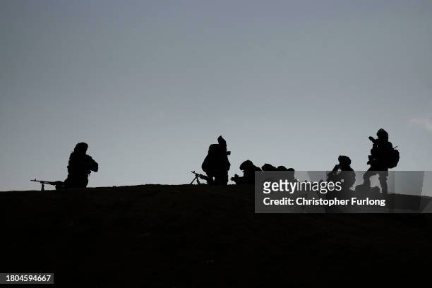 Israeli infantry soldiers, seen in silhouette, take part in a live firing tactical advance exercise near the border in readiness for possible...
