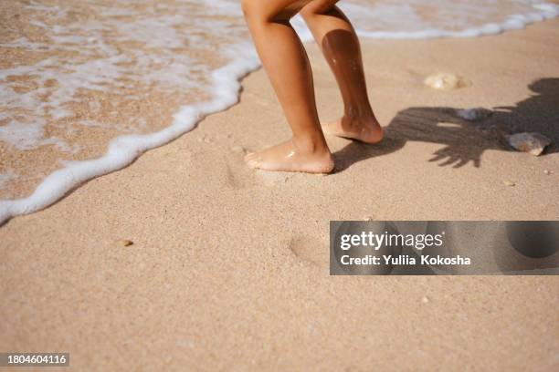 cropped shot of lovely little girl jumping to the sea waves at the beach. having fun at beach on a sunny summer day - feet run in ocean stock pictures, royalty-free photos & images
