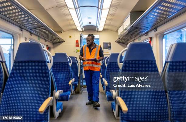 african man inspecting inside of a public transport train in maintenance facility - machinist stockfoto's en -beelden