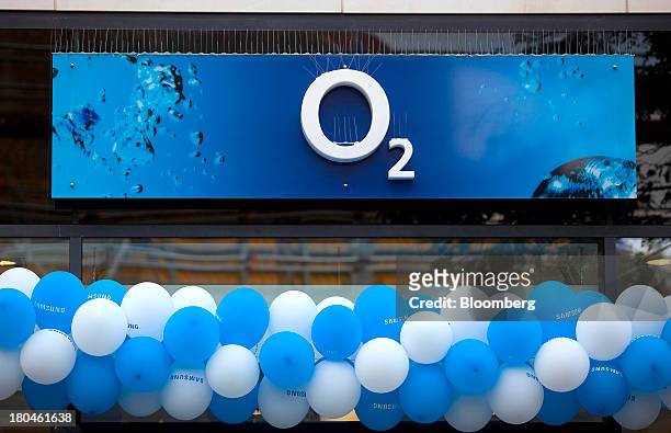 String of promotional balloons for the O2 brand sit underneath a sign outside an O2 store operated by Telefonica SA in Leipzig, Germany, on Thursday,...
