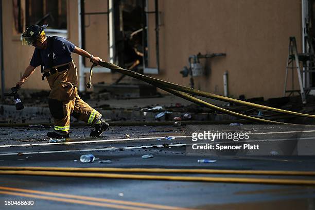 Firefighter pulls a hose at the scene of a massive fire that destroyed dozens of businesses along an iconic Jersey shore boardwalk on September 13,...