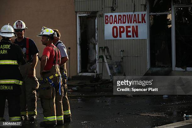 Firefighters stand at the scene of a massive fire that destroyed dozens of businesses along an iconic Jersey shore boardwalk on September 13, 2013 in...