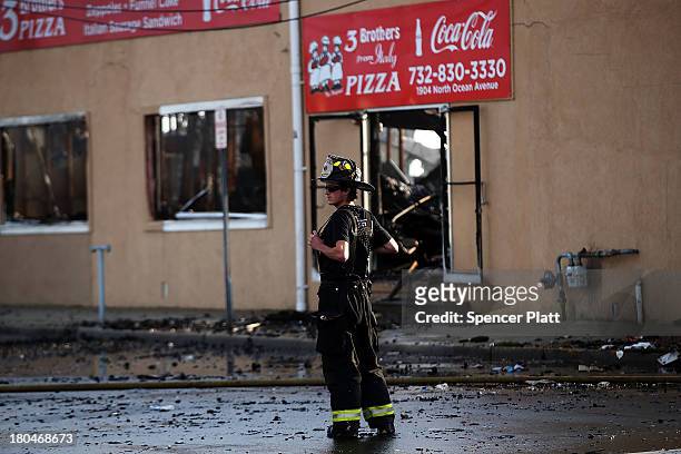 Firefighter stands at the scene of a massive fire that destroyed dozens of businesses along an iconic Jersey shore boardwalk on September 13, 2013 in...