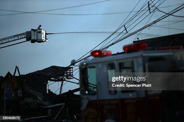 Firefighter sprays water on a hot-spot at the scene of a massive fire that destroyed dozens of businesses along an iconic Jersey shore boardwalk on...