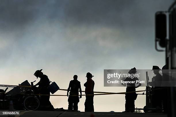 Firefighters stand at the scene of a massive fire that destroyed dozens of businesses along an iconic Jersey shore boardwalk on September 13, 2013 in...