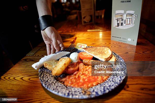 Wetherspoon Plc employee serves a full English cooked breakfast to a customer in this arranged photograph taken inside one of the company's pubs in...
