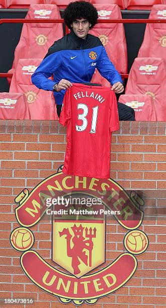 Marouane Fellaini of Manchester United poses with a United shirt after the press conference to announce his signing at Old Trafford on September 13,...