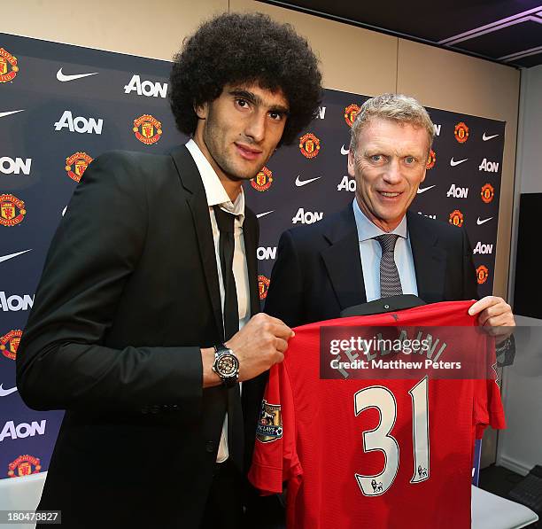 Marouane Fellaini of Manchester United poses with manager David Moyes and a United shirt after the press conference to announce his signing at Old...