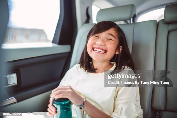 cheerful teenage girl drinking water in back seat of car while taking a break during the family road trip - back seat stock pictures, royalty-free photos & images