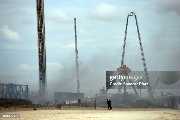 Two people walk near the destroyed remains of businesses along an iconic Jersey shore boardwalk on September 13, 2013 in Seaside Heights, New Jersey....