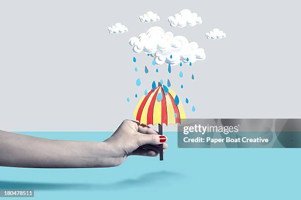 hand holding paper craft umbrella under rain cloud - rain umbrella stock pictures, royalty-free photos & images