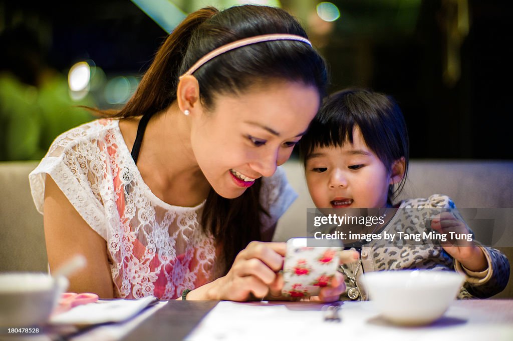 Young mom & toddler using smartphone before dinner
