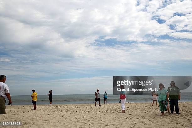 People walk onthe beach near the scene of a massive fire that destroyed dozens of businesses along an iconic Jersey shore boardwalk on September 13,...