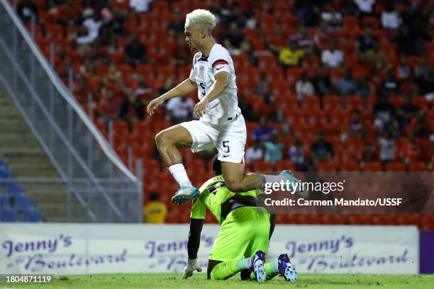 Antonee Robinson of the United States jumps over Denzil Smith of Trinidad and Tobago during the first half at Hasely Crawford Stadium on November 20,...