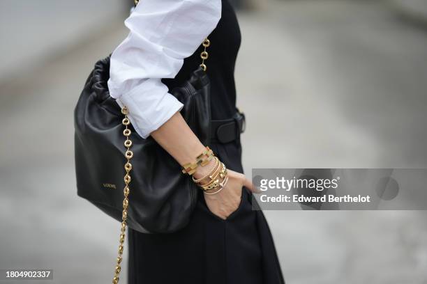 Heart Evangelista wears golden Cartier bracelets / jewelry, a black leather Loewe bag with a golden chain, during a street style fashion photo...