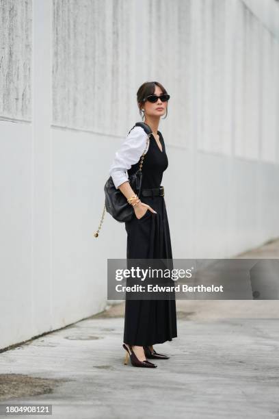 Heart Evangelista wears Prada sunglasses, a white shirt, a black wool ribbed low-neck tank top, a dark navy blue pleated long maxi skirt, a black...