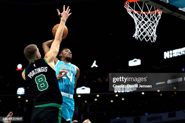 Brandon Miller of the Charlotte Hornets attempts to dunk the ball during the first half of an NBA game against Kristaps Porzingis of the Boston...