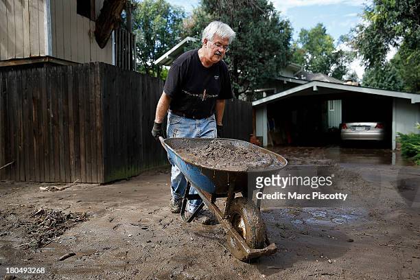 Jeff Kandyba of Boulder, Colorado removes a wheelbarrow full of silt from his driveway September 13, 2013 in Boulder, Colorado. Heavy rains for the...