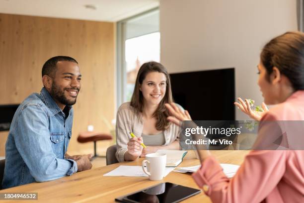 un conseiller financier conseille un couple multiracial à domicile - satisfaction client photos et images de collection