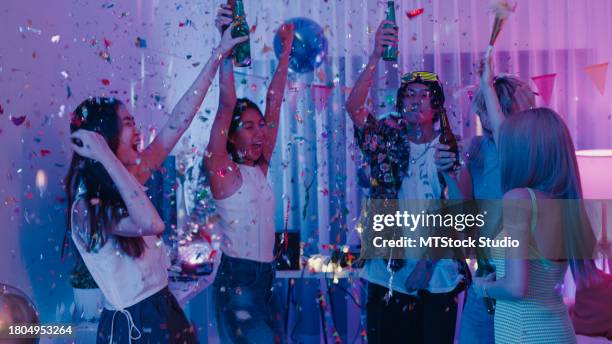 diverse group of friends getting drunk and dancing moving rhythmically under falling confetti at colorful house party at night. multicultural friends having fun together college house party. - party under stock pictures, royalty-free photos & images