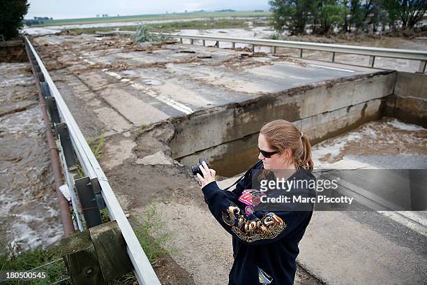 Leah Sorber of Longmont, Colorado takes pictures of the flooding and damage on a partially collapsed bridge on Weld County Road 1 on September 13,...