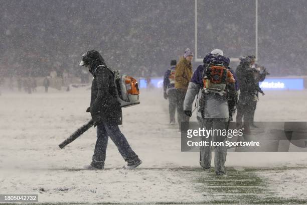 Grounds crew members try to clear snow from the field during a time in a Big 12 football game between the Iowa State Cyclones and Kansas State...