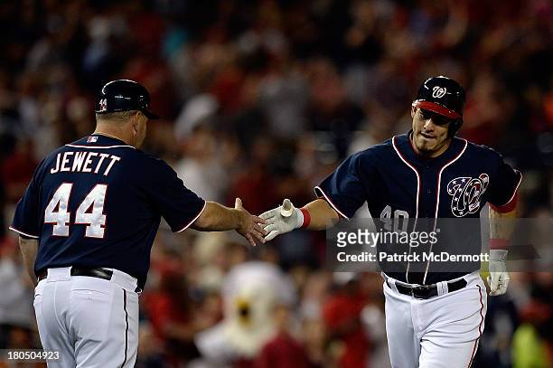 Wilson Ramos of the Washington Nationals celebrates with third base coach Trent Jewett after hitting a solo home run in the second inning against the...