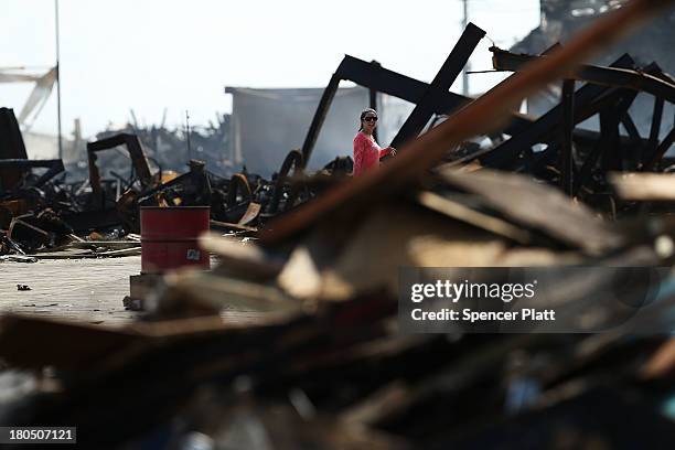 Woman walks through the scene of a massive fire that destroyed dozens of businesses along an iconic Jersey shore boardwalk on September 13, 2013 in...