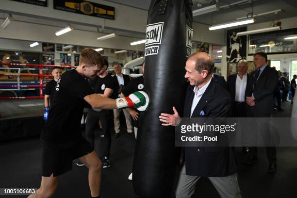 Prince Edward, Duke of Edinburgh, holds the punching bag during boxing with 21 year old Marlon Sevehon from the Youth Boxing Program at the Police...