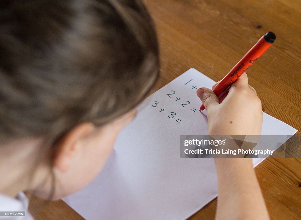 Young girl working out simple maths problems.