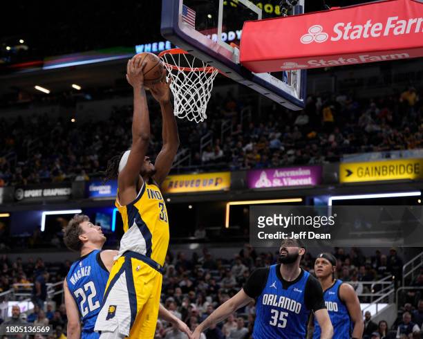 Myles Turner of the Indiana Pacers dunks against Franz Wagner and Goga Bitadze of the Orlando Magic at Gainbridge Fieldhouse on November 19, 2023 in...