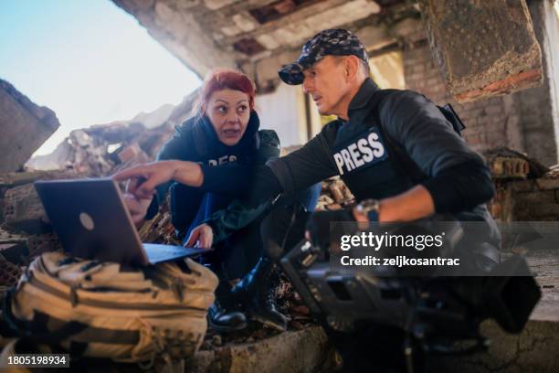 kriegsreporter arbeiten am laptop und übertragen die lage live - fernsehreporter stock-fotos und bilder