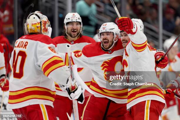 Dan Vladar, Chris Tanev, MacKenzie Weegar and Rasmus Andersson of the Calgary Flames celebrate their overtime win against the Seattle Kraken 4-3at...