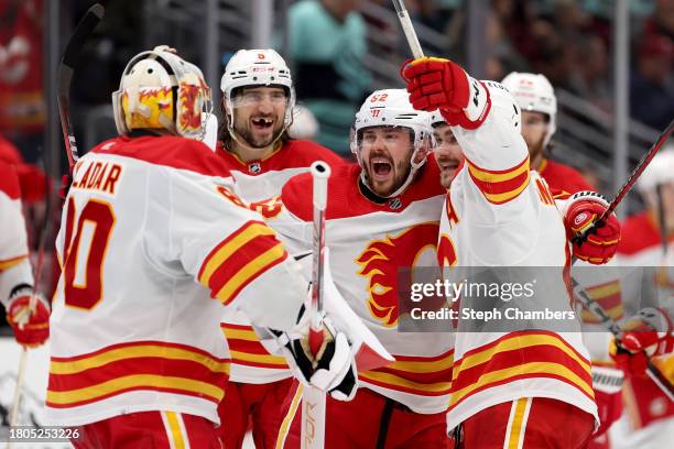 Dan Vladar, Chris Tanev, MacKenzie Weegar and Rasmus Andersson of the Calgary Flames celebrate their overtime win against the Seattle Kraken 4-3at...