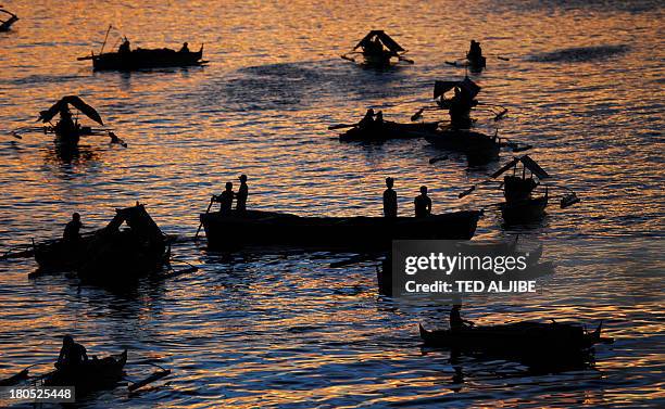 Evacuees affected by the stand-off between Philippine government forces and Muslim rebels sit anchored in their wooden boats used also as temporary...