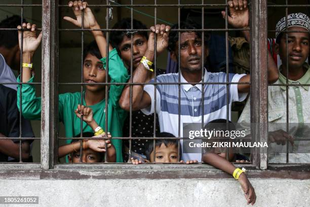 This picture taken on November 26, 2023 shows recently arrived Rohingya refugees looking on from their shared quarters at a temporary Indonesian...