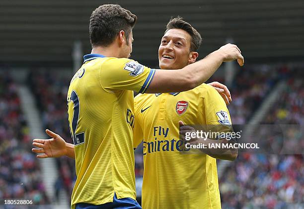 Arsenals German midfielder Mesut Ozil congratulates Arsenal's French striker Olivier Giroud after Giroud scored their first goal during the English...